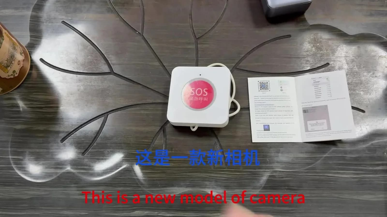 Wall SOS-button–style camera — desk shot with cable